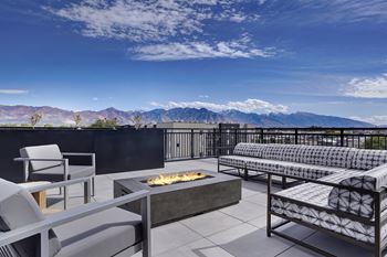 A patio with a fire pit and seating area overlooking a mountain range.